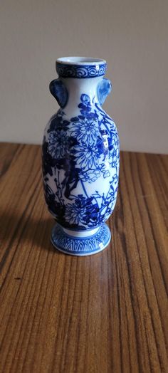 a blue and white vase sitting on top of a wooden table