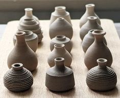 many vases are lined up on a wooden board with holes in the top one