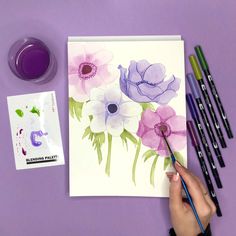 someone is painting flowers with watercolors on paper