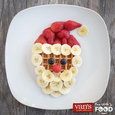 a white plate topped with waffles and fruit covered in a santa claus face