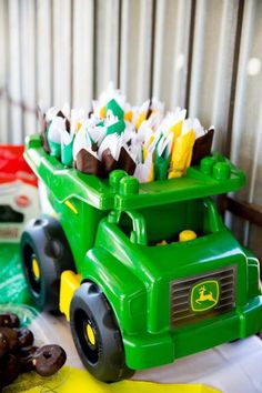 a green toy truck filled with chocolate candies on top of a white table cloth