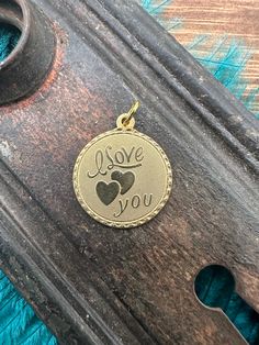 HOW SWEET! Round tag charm with ,"I LOVE YOU" and a double heart.  These charms are new and unworn, made from decades old stamping machines.  This is a single sided charm with a plain back and can be worn a variety of ways including as a pendant, earrings, on a bracelet, anklet or on a charm necklace. These charms are made of raw brass which will patina over time and may already have some patina. There may be color variations in the brass due to this and differences in each piece.  Please refer Vintage Heart Charms For Gifts, Vintage Heart Charms For Gift, Vintage Charm For Valentine's Day Gift, Engraved Charms For Valentine's Day Anniversary, Engraved Charms For Anniversary On Valentine's Day, Valentine's Day Gift Vintage Charm, Valentine's Day Gift: Vintage Charm, Gold Engraved Charms For Valentine's Day, Stamping Jewelry