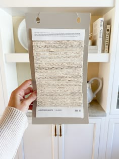 a person holding up a piece of fabric in front of a book shelf filled with books