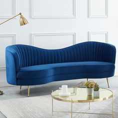 a blue couch sitting on top of a white rug next to a table and lamp