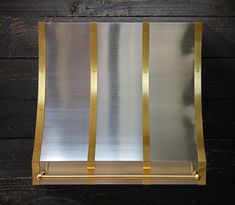 a gold and silver metal shelf on a wooden wall