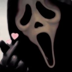 a person in a ghost mask holding a cell phone up to their face with hearts on it