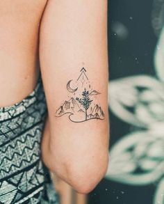 a woman's arm with a tattoo on it that has mountains and a tree