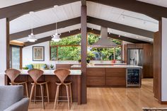 an open kitchen and living room with wood flooring, white walls and ceiling beams