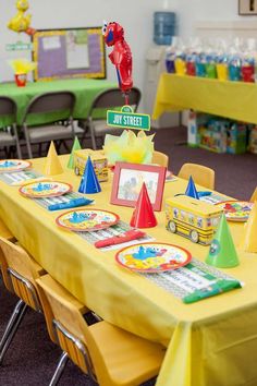 a yellow table topped with lots of colorful plates and place settings for children's birthdays