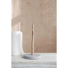 a white toilet paper holder with a wooden stick sticking out of it