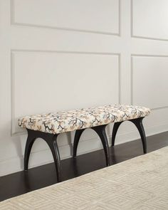 a bench sitting on top of a hard wood floor next to a white painted wall