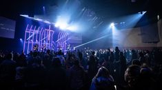 a group of people standing on top of a stage under bright blue lights at night