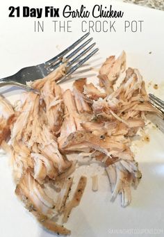 shredded chicken sitting on top of a white plate next to a fork and knife with text overlay reading 21 day fix garlic chicken in the crock pot