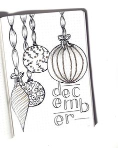 an open notebook with some ornaments hanging from it's sides and the words december written in black ink