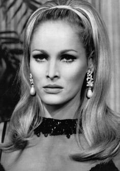 an old black and white photo of a woman with long blonde hair wearing large earrings