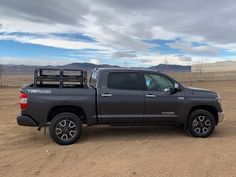 a gray truck parked in the middle of a dirt field