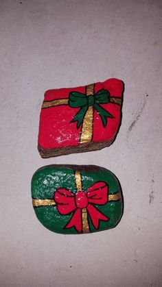 two decorated rocks sitting on top of a white counter covered in green and red wrapping