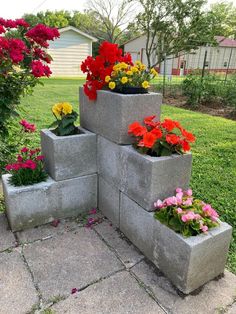 four cement planters with flowers in them