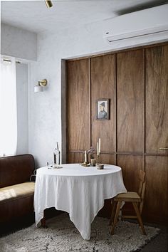 a white table and chair in a room with wood paneling on the wall behind it