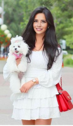 a woman holding a white dog in her hands