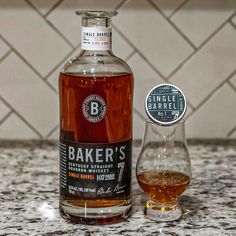 a bottle of baker's whiskey next to a glass on a marble countertop