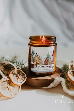 a candle that is sitting on top of a table next to orange slices and pine cones