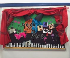 a bulletin board with musical notes on it and red curtains hanging from the wall above