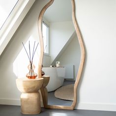 a mirror sitting on top of a wooden table next to a vase