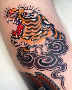 a close up of a tattoo on a person's leg with a tiger and clouds in the background