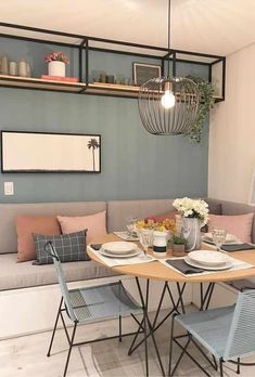 a dining room table with chairs and plates on it, in front of a couch