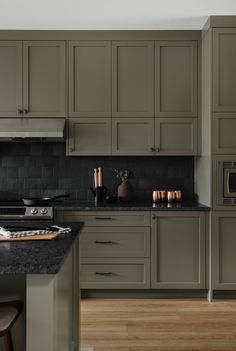 a kitchen with green cabinets and black counter tops, along with an oven in the center