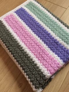 a crocheted blanket sitting on top of a wooden floor next to a pink circle