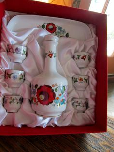 a white vase and cups in a red box