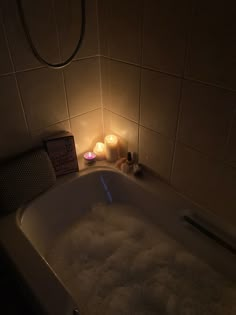 a bathtub filled with foam next to two candles