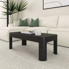 a black coffee table sitting on top of a white couch in front of a plant