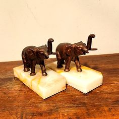 two figurines of elephants standing on blocks of soap sitting on a wooden table