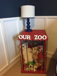 a red cage with stuffed animals in it next to a lamp