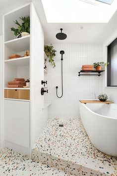 a bathroom with a skylight above the bathtub and shelves on the wall behind it