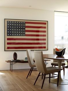 an american flag hanging on the wall above a dining room table with chairs around it