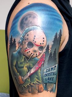 a man with a tattoo on his arm holding a knife and wearing a mask that says camp crystal lake