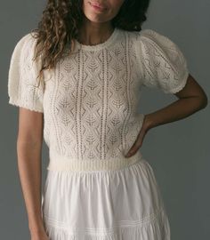 a woman wearing a white dress with short sleeves and a frilled skirt is posing for the camera