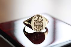 a signet ring sitting on top of a wooden table in front of a mirror