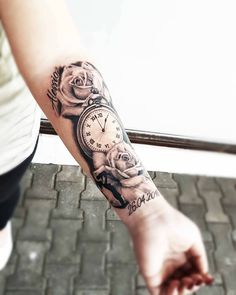 a woman's arm with a clock and roses tattoo on it