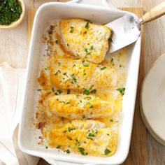 a casserole dish with chicken and cheese in it on a wooden table next to a white plate