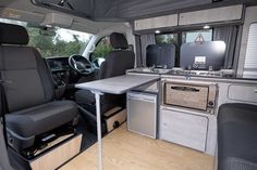 the interior of a camper van with an oven and table in the back area