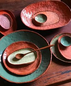 three bowls with spoons in them sitting on a wooden table next to each other