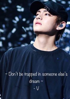 a young man with ear buds in his ears wearing a black shirt and cap that says, don't be trapped in someone else's dream - v