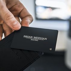 a person holding up a black business card in their left hand, with the words bran meehan racing on it