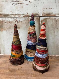 three stacks of different colored yarn sitting on top of a wooden table next to each other