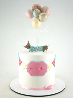 a birthday cake with balloons on top and the name guada written in pink letters